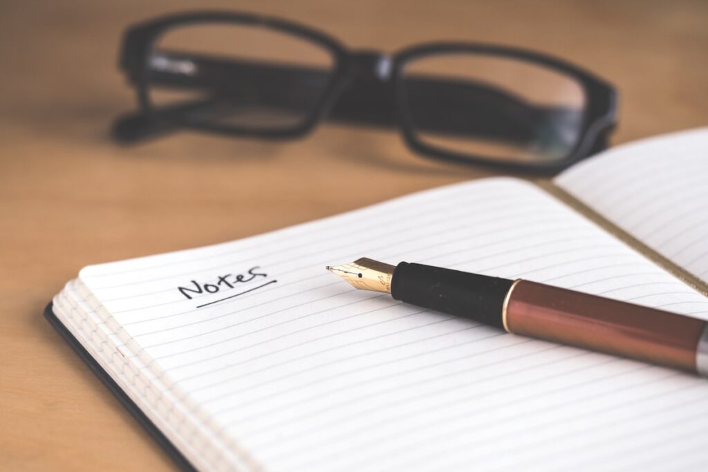Woman writing in a journal at a wooden desk with coffee nearby