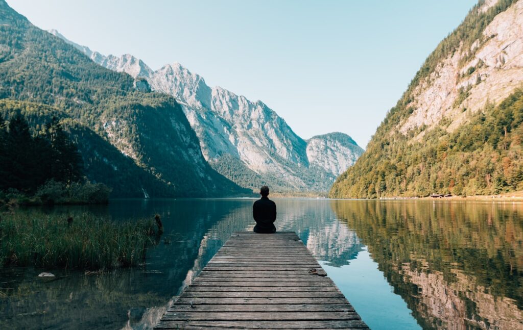 Person sitting in mindful meditation position in a quiet natural setting
